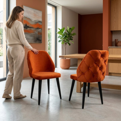 Gepolsterter Holzstuhl orange Chesterfield auf schwarzen Beinen das Esszimmer